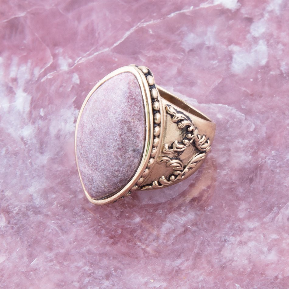 Gold ring with a pink stone on a pink marble background
