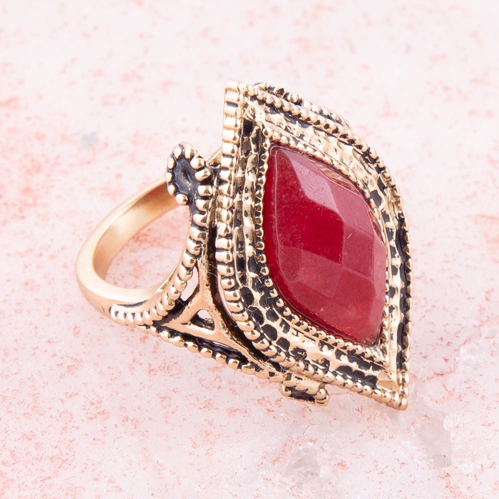 Gold ring with a red gemstone on a pink background