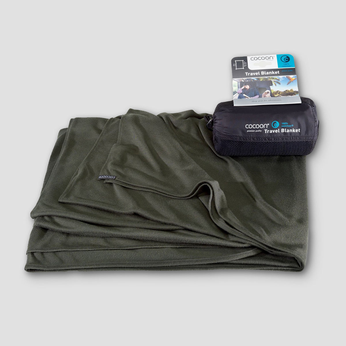 Folded green travel blanket with packaging on a light gray background