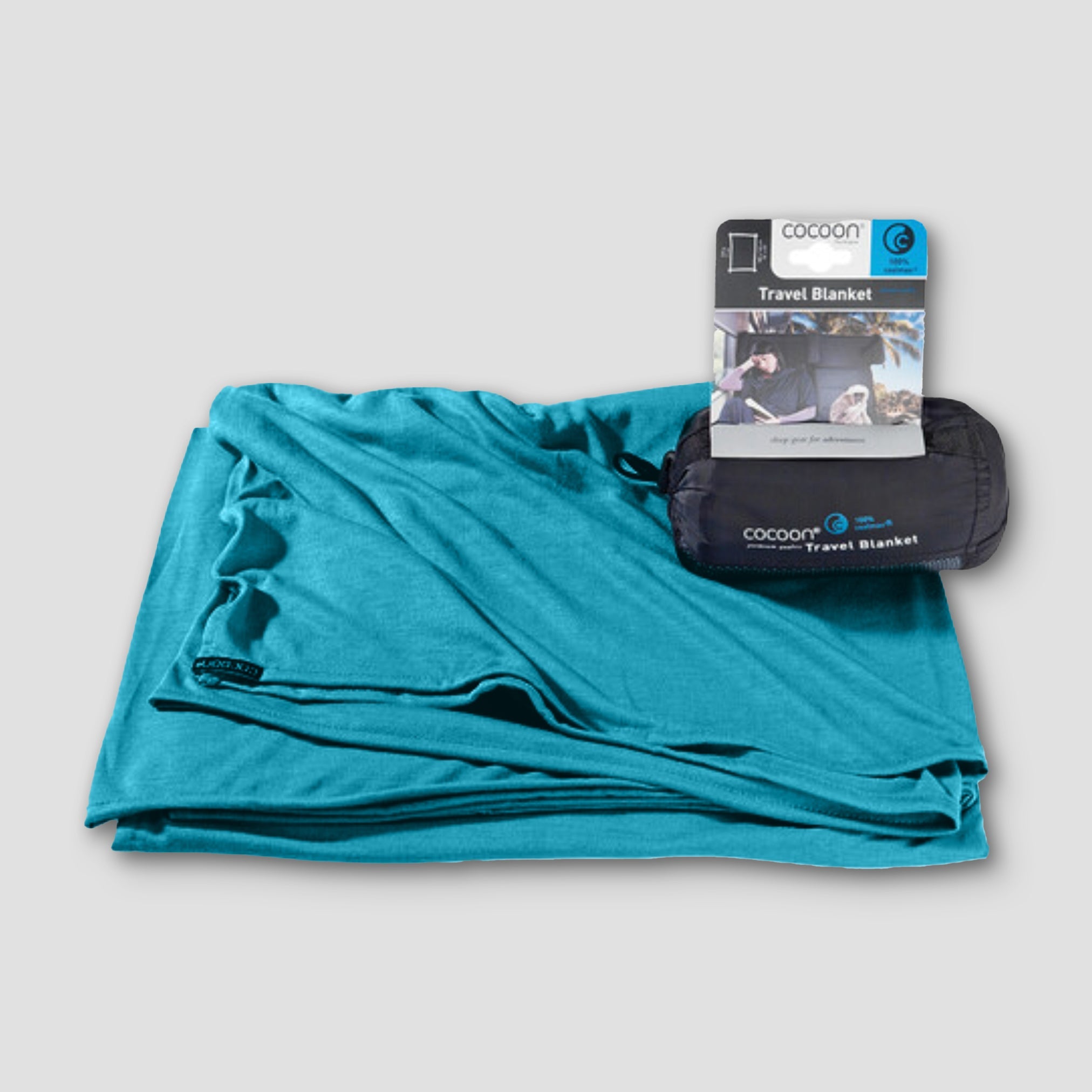 Teal travel blanket with packaging on a light gray background