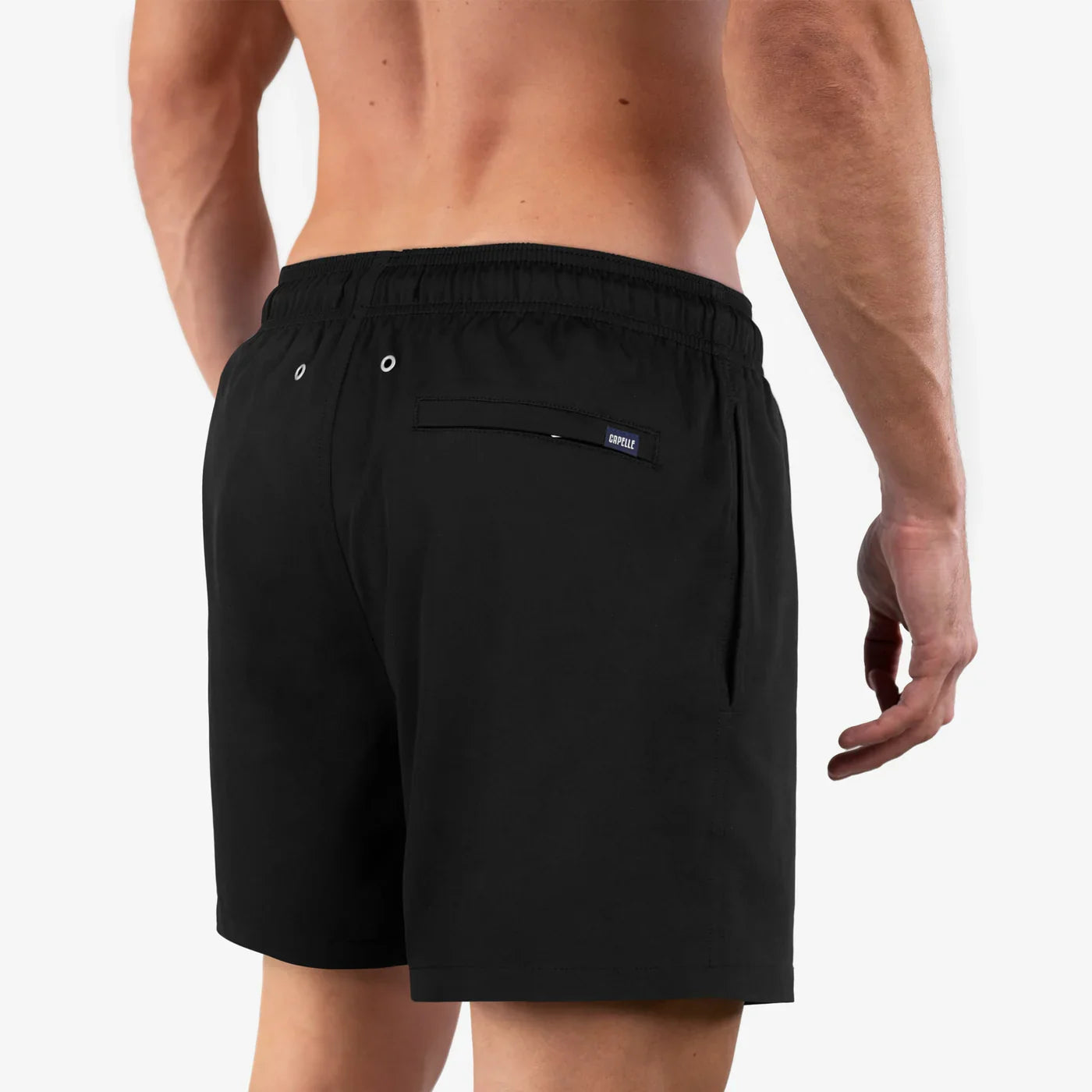 Black swim shorts worn by a person on a plain background