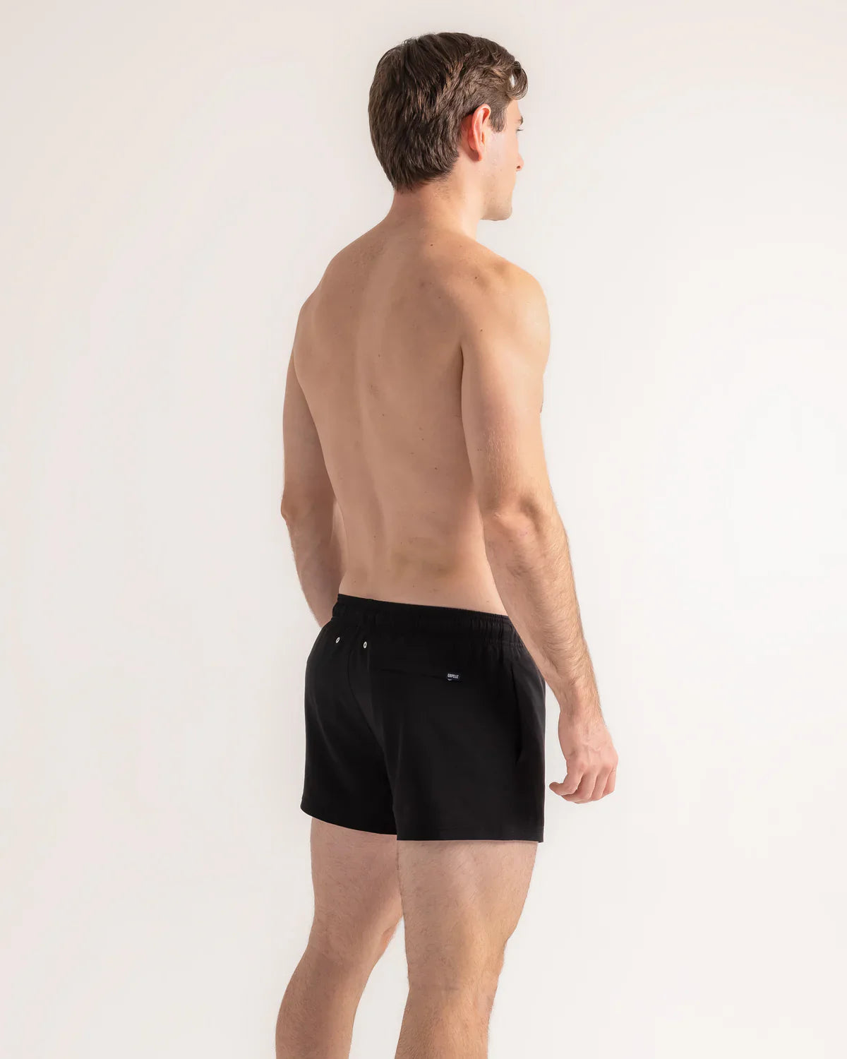 Man wearing black swim shorts on a white background