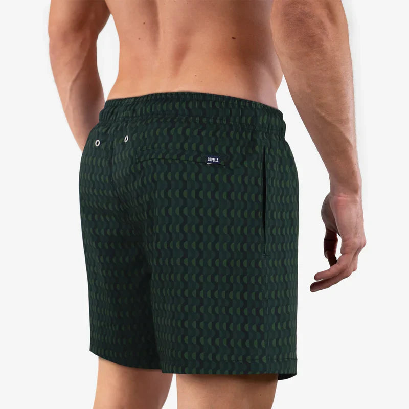 Green patterned swim shorts worn by a person on a white background