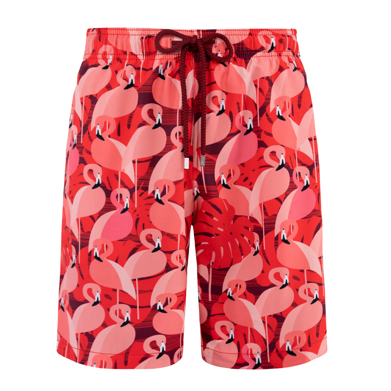 Red swim shorts with pink flamingo pattern on a white background