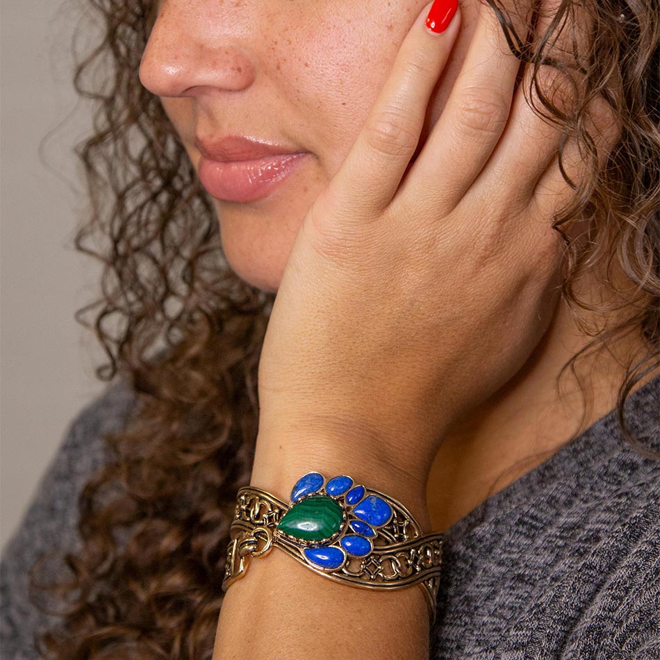 Close-up of a woman wearing a decorative bracelet with blue and green stones.