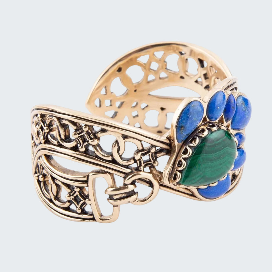 Gold ring with blue and green gemstones on a white background