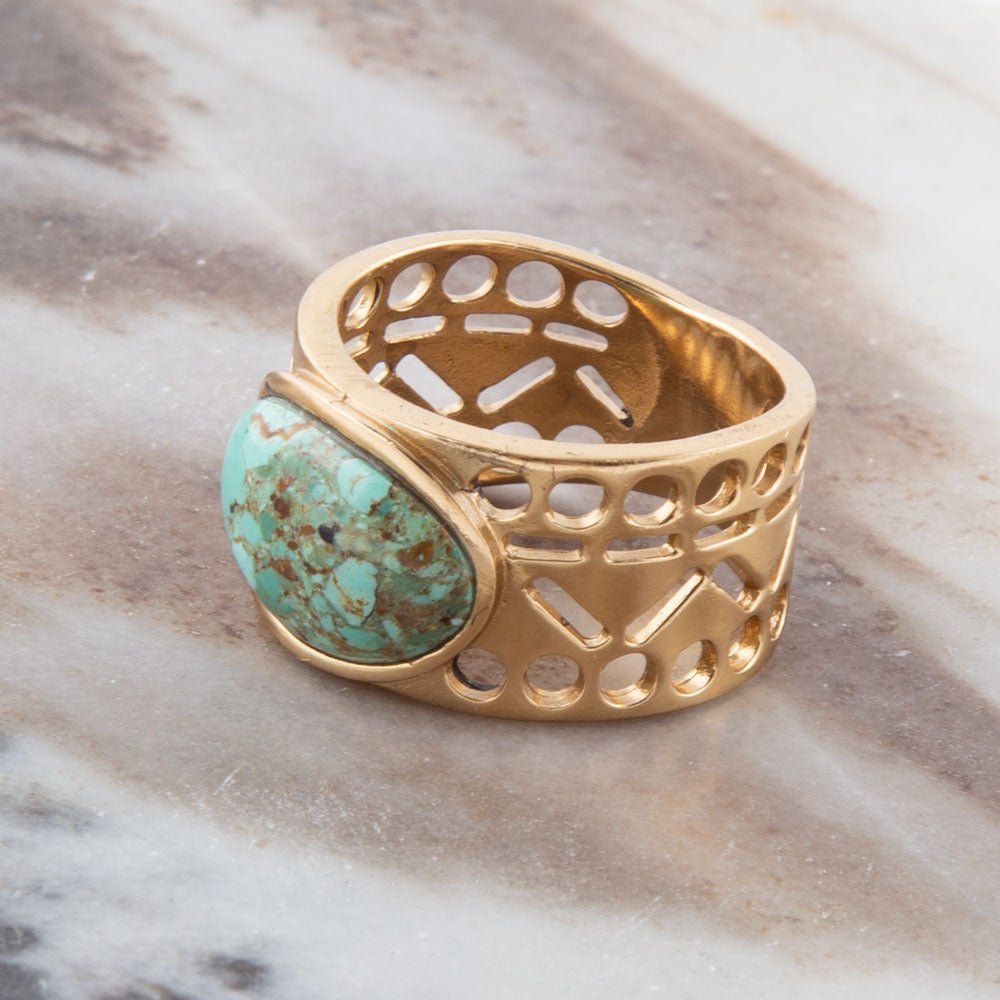 Gold ring with turquoise stone on a marble surface