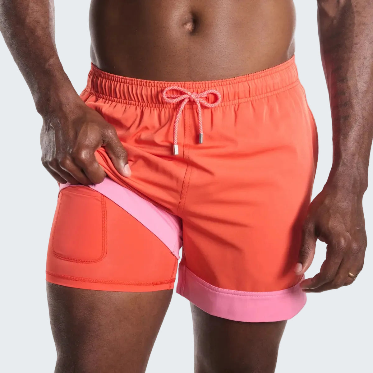 Person wearing a two-tone orange and pink swim shorts on a white background