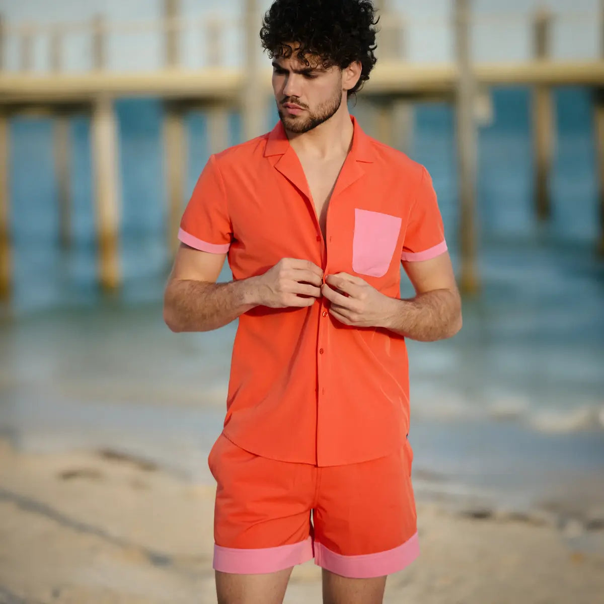 Man wearing an orange and pink outfit on a beach