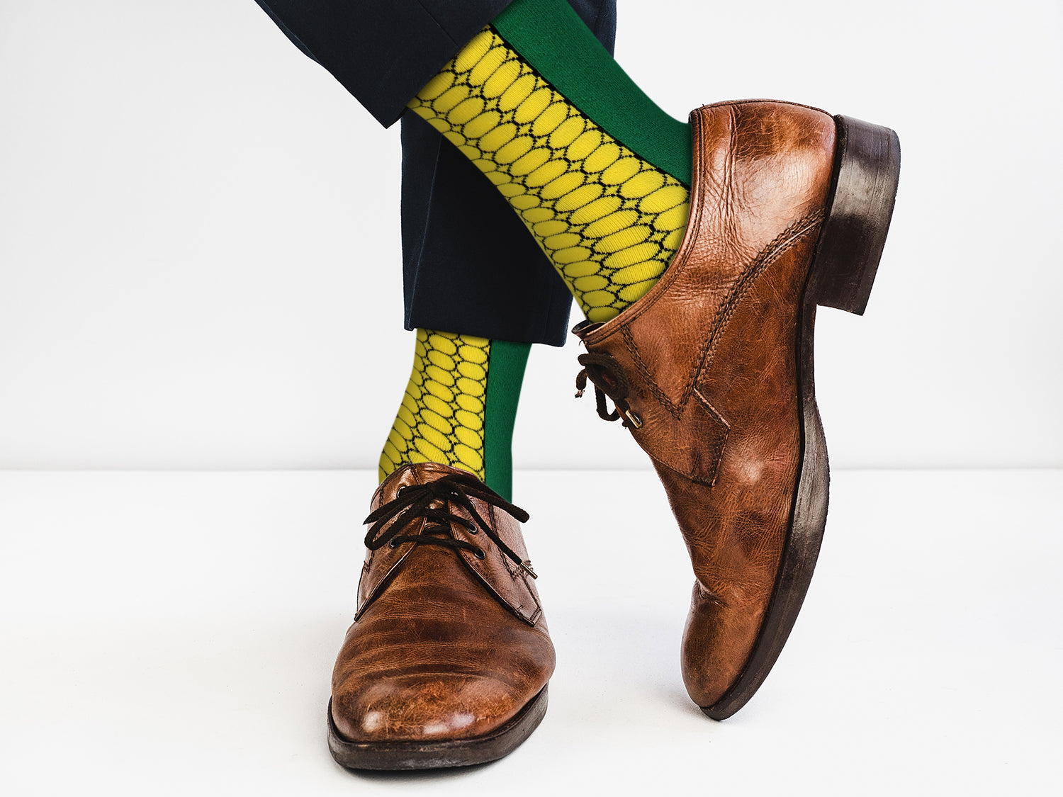 Brown dress shoes and yellow snake skin pattern socks on a white background