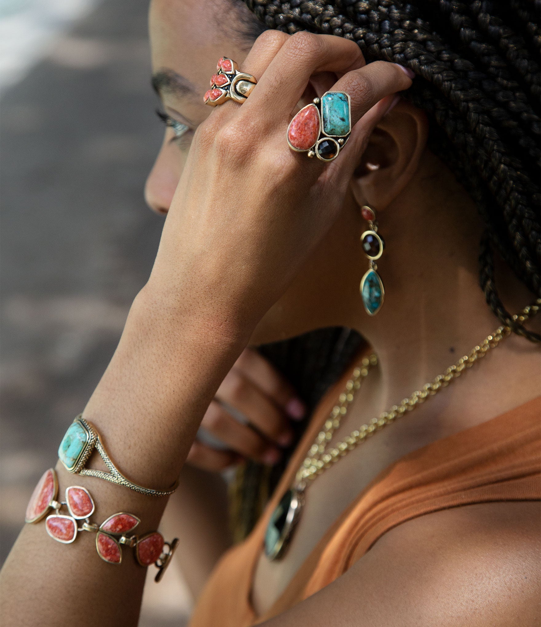 Person wearing colorful jewelry including rings and bracelets with a blurred background