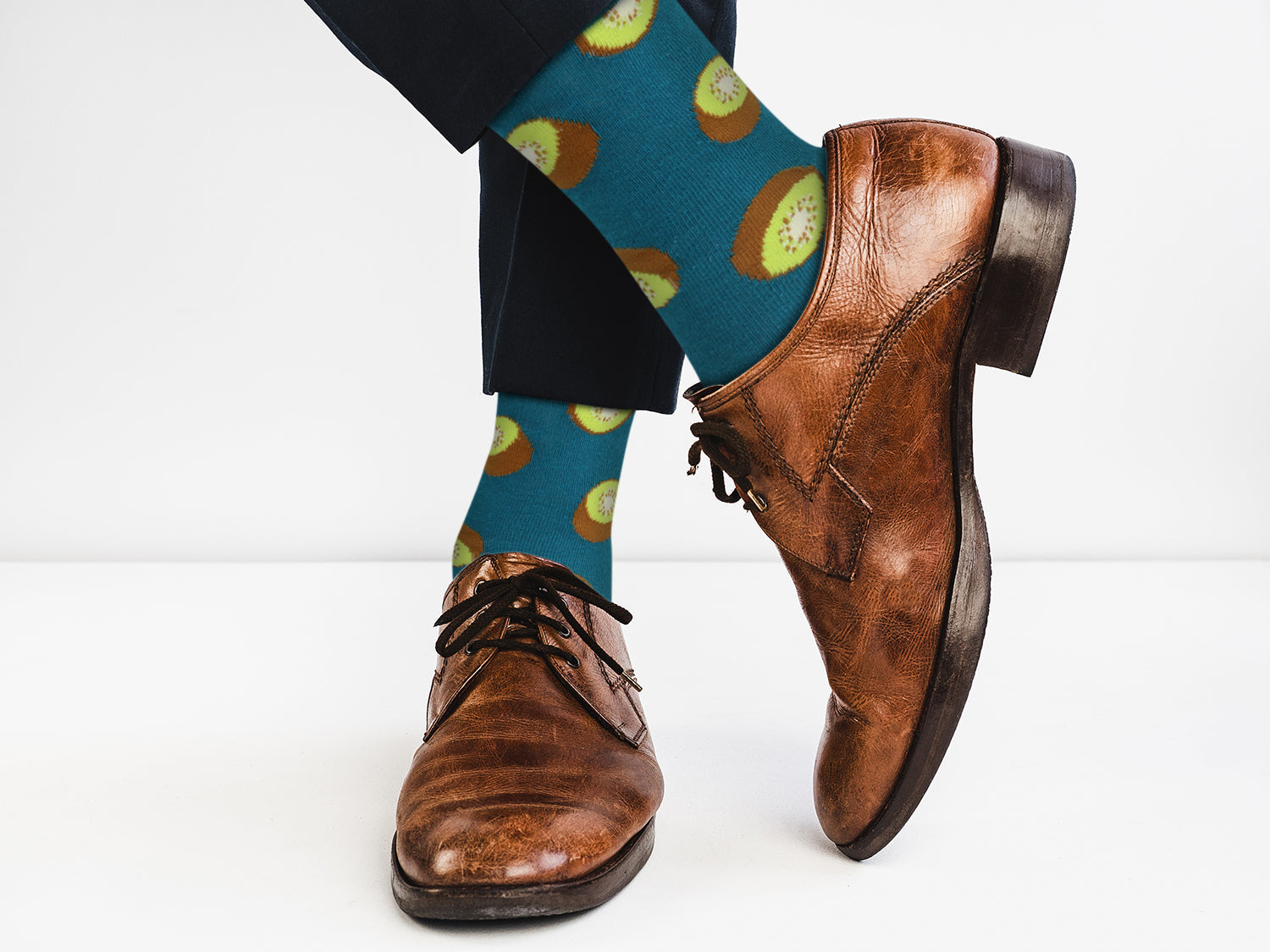 Brown dress shoes and blue socks with kiwi pattern on a white background