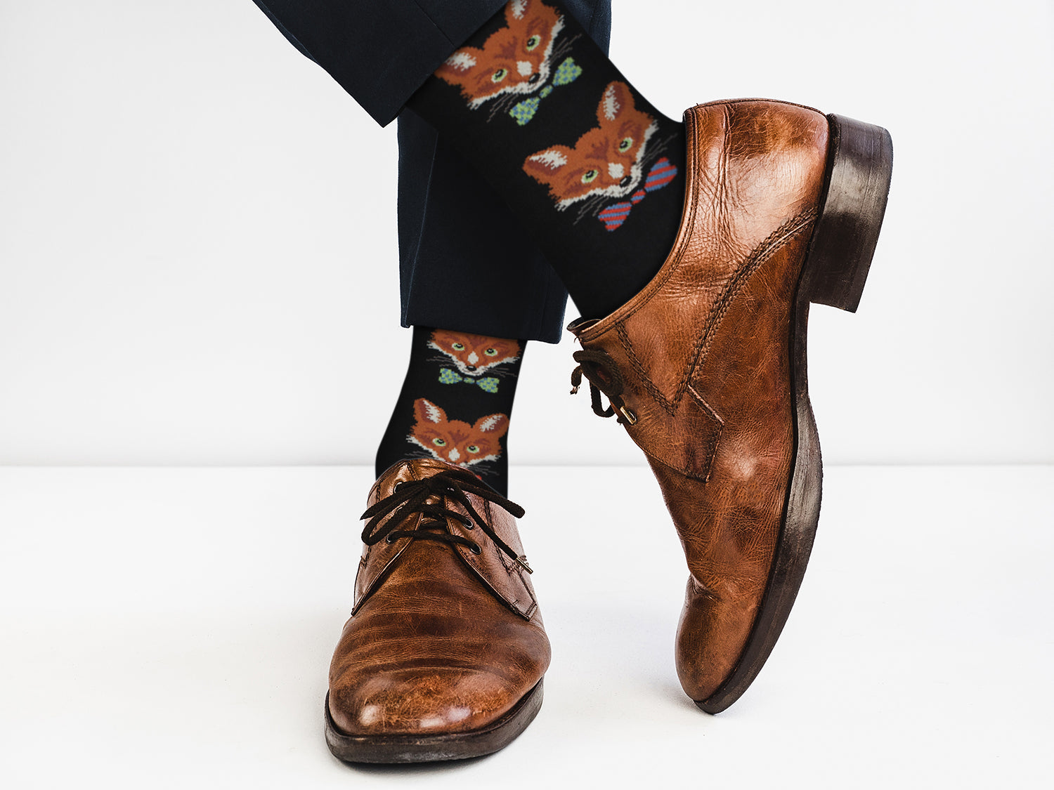 Brown dress shoes and fox-patterned socks on a white background