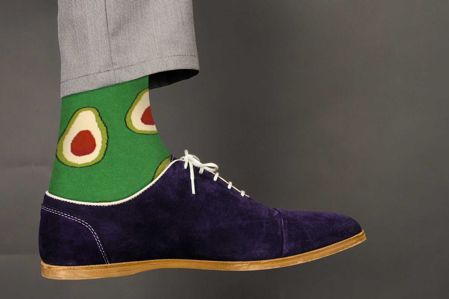 Navy suede shoe with avocado-themed sock on a gray background
