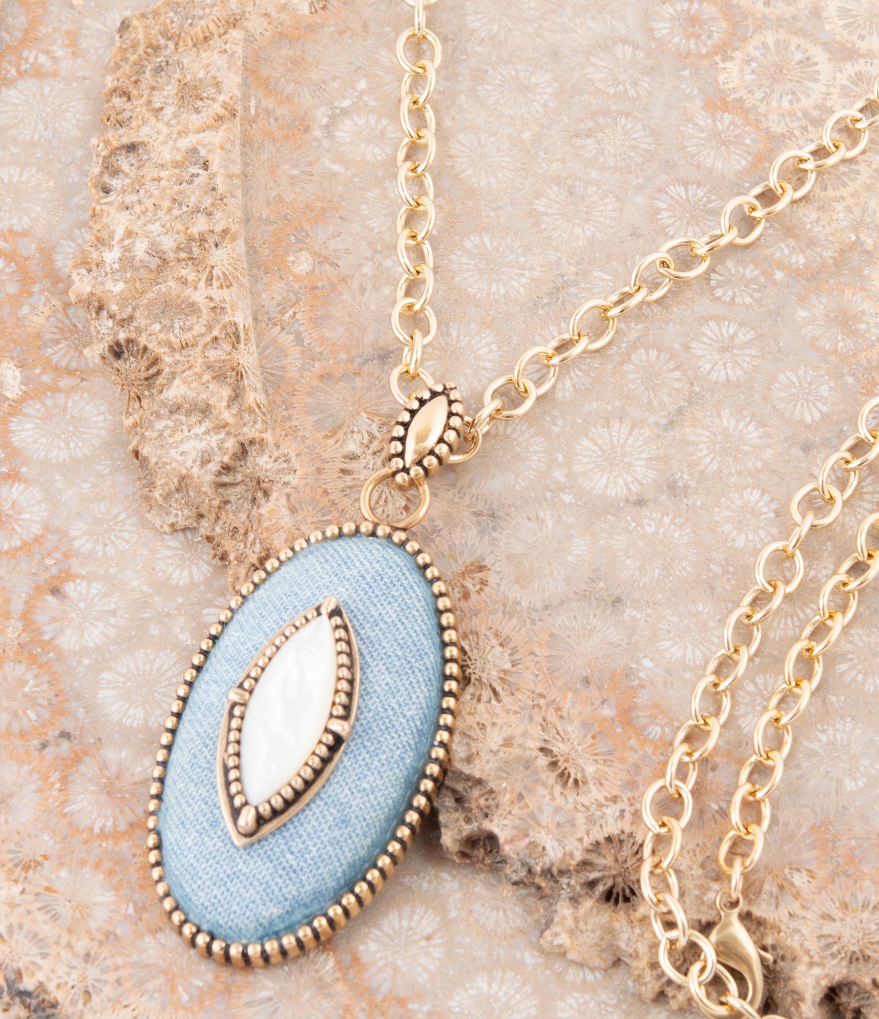 Necklace with a light blue pendant on a textured beige surface