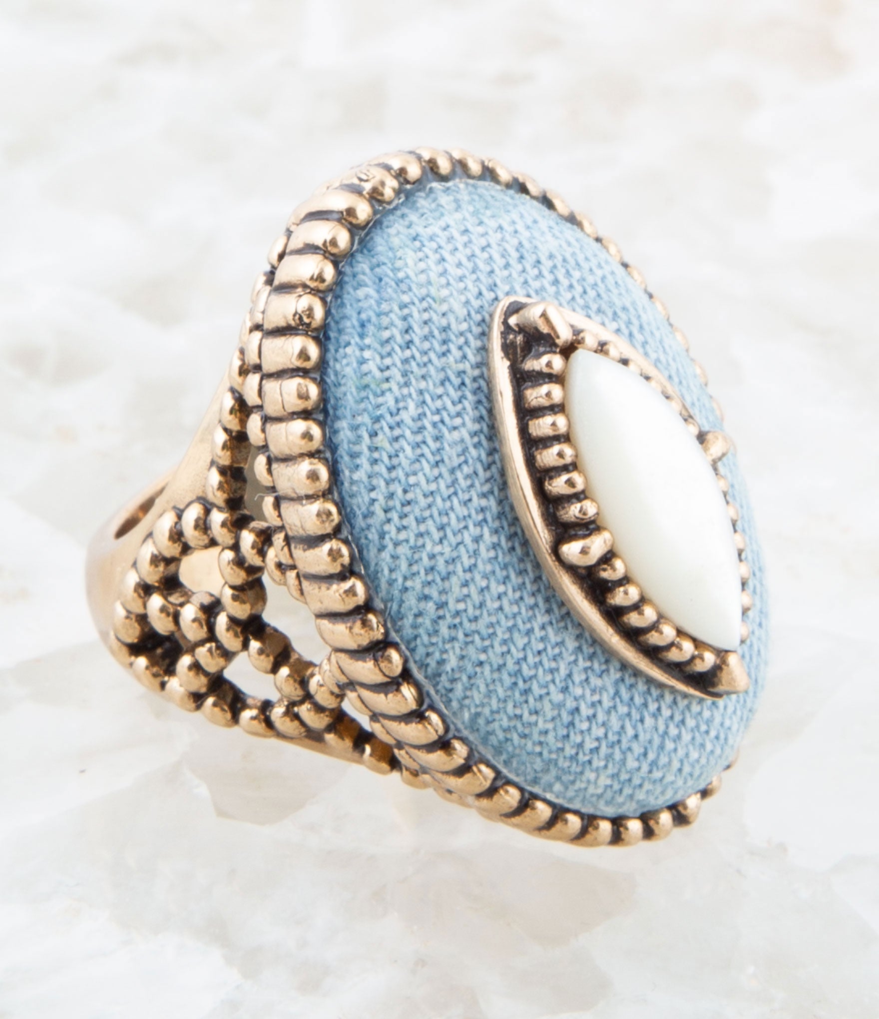 Ring with blue fabric center and gold detailing on a white background