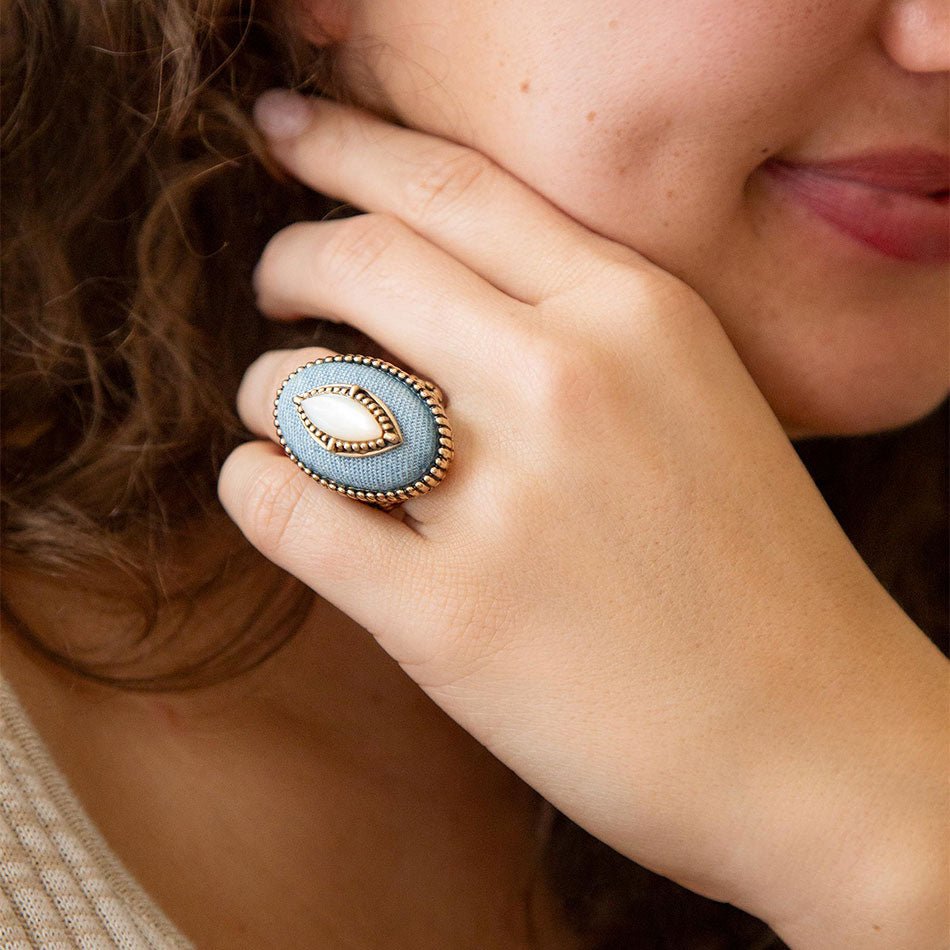 Close-up of a person wearing a decorative ring with a blue stone and gold band.