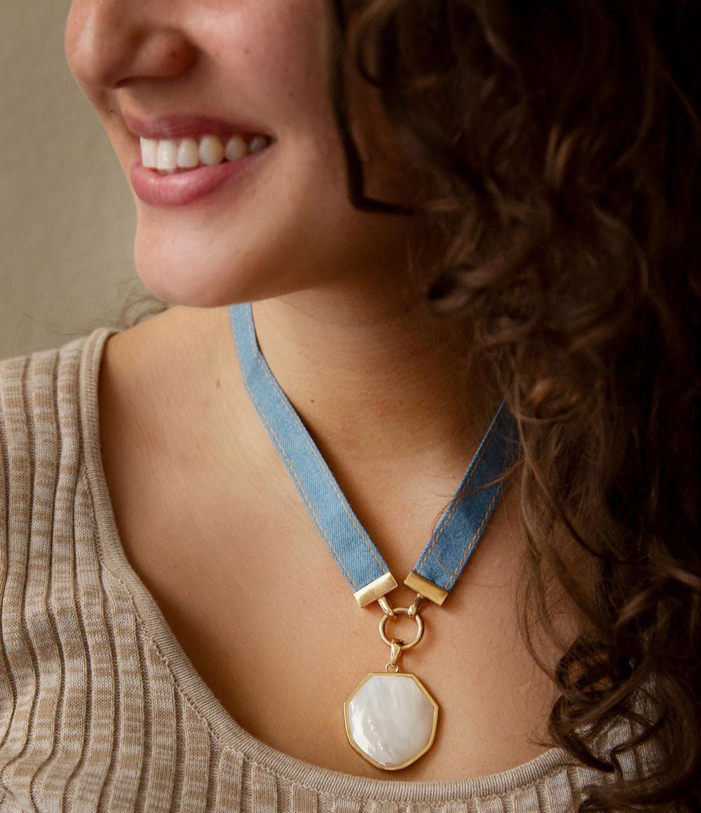 Woman wearing a necklace with a blue strap and gold clasp