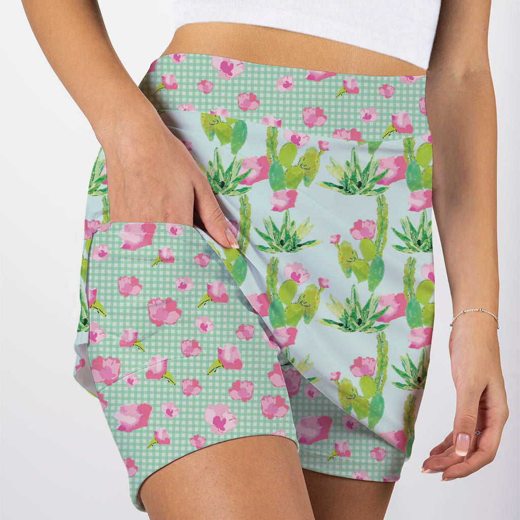 Person wearing a skirt with a cactus and floral pattern on a light blue background