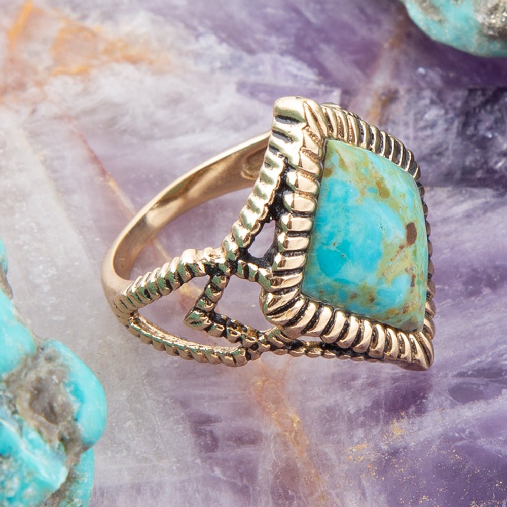 Gold ring with turquoise stone on a textured purple surface