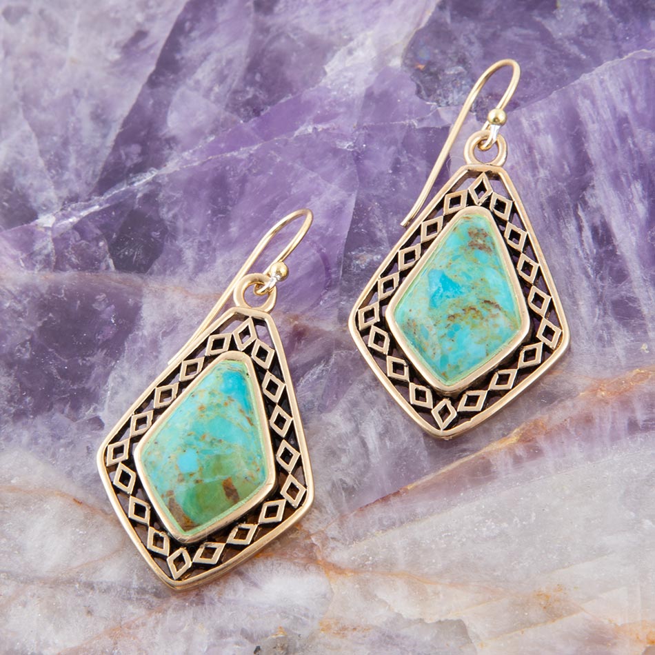 Gold-framed turquoise earrings on a textured stone background