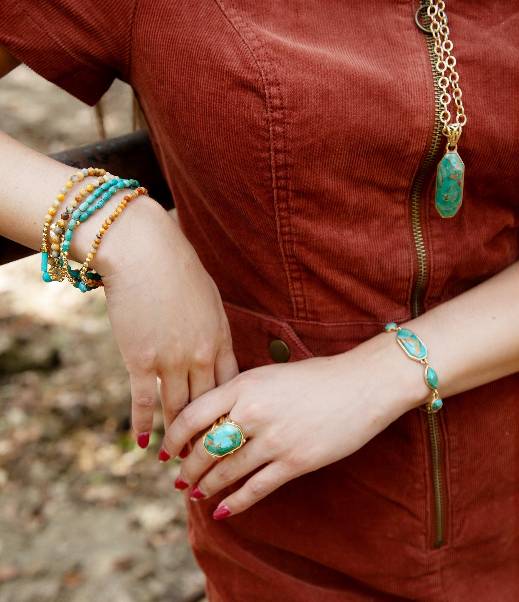 Person wearing multiple turquoise bracelets and a ring on a blurred natural background