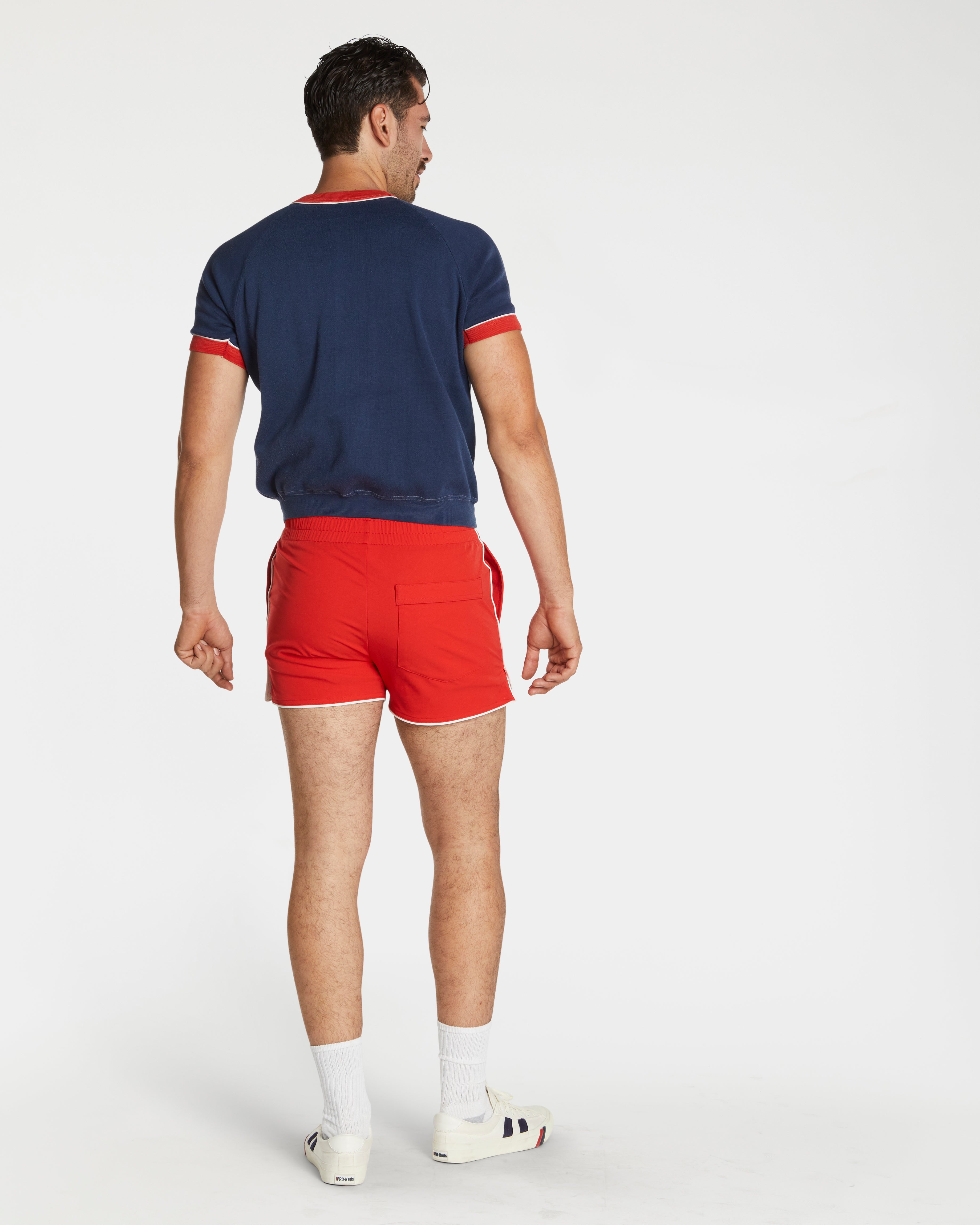 Person wearing a navy shirt with red trim and red shorts on a white background