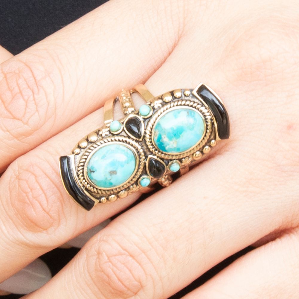 Ring with turquoise stones and gold accents on a finger