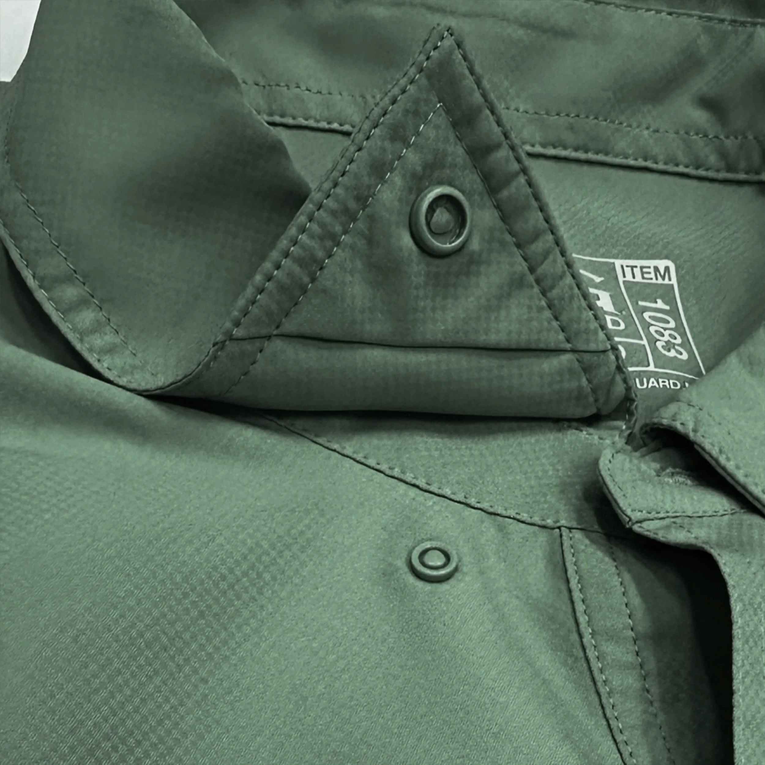 Close-up of a green jacket with a button and brand label.