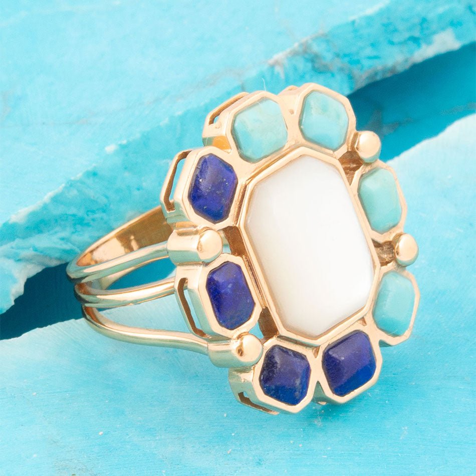 Gold ring with blue and turquoise stones on a blue background