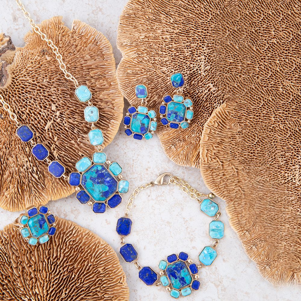 Blue and gold jewelry set on a textured beige surface