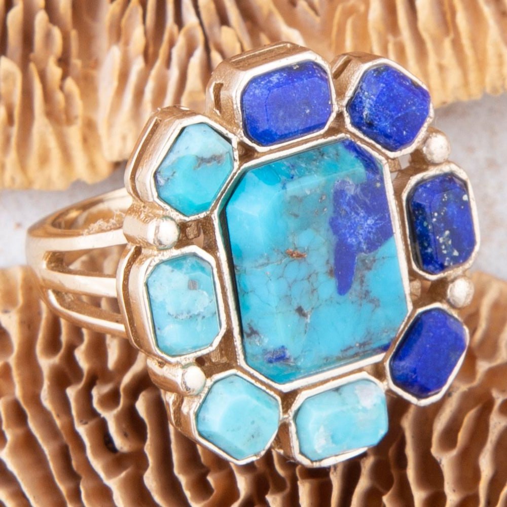 Gold ring with blue and turquoise stones on a textured surface