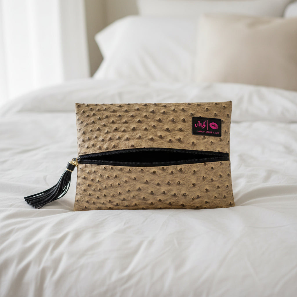 Beige clutch bag with black polka dot pattern and tassel on a light gray background