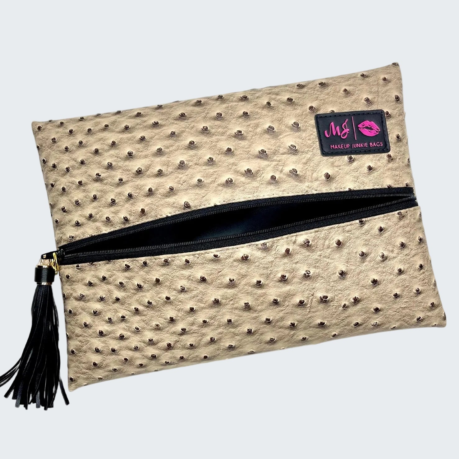 Beige clutch bag with black zipper and tassel on a white background