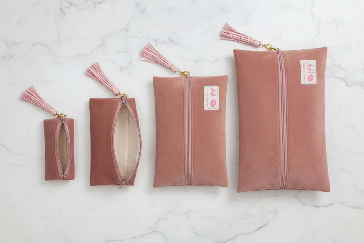 Pink suede clutch bag with a tassel on a white background