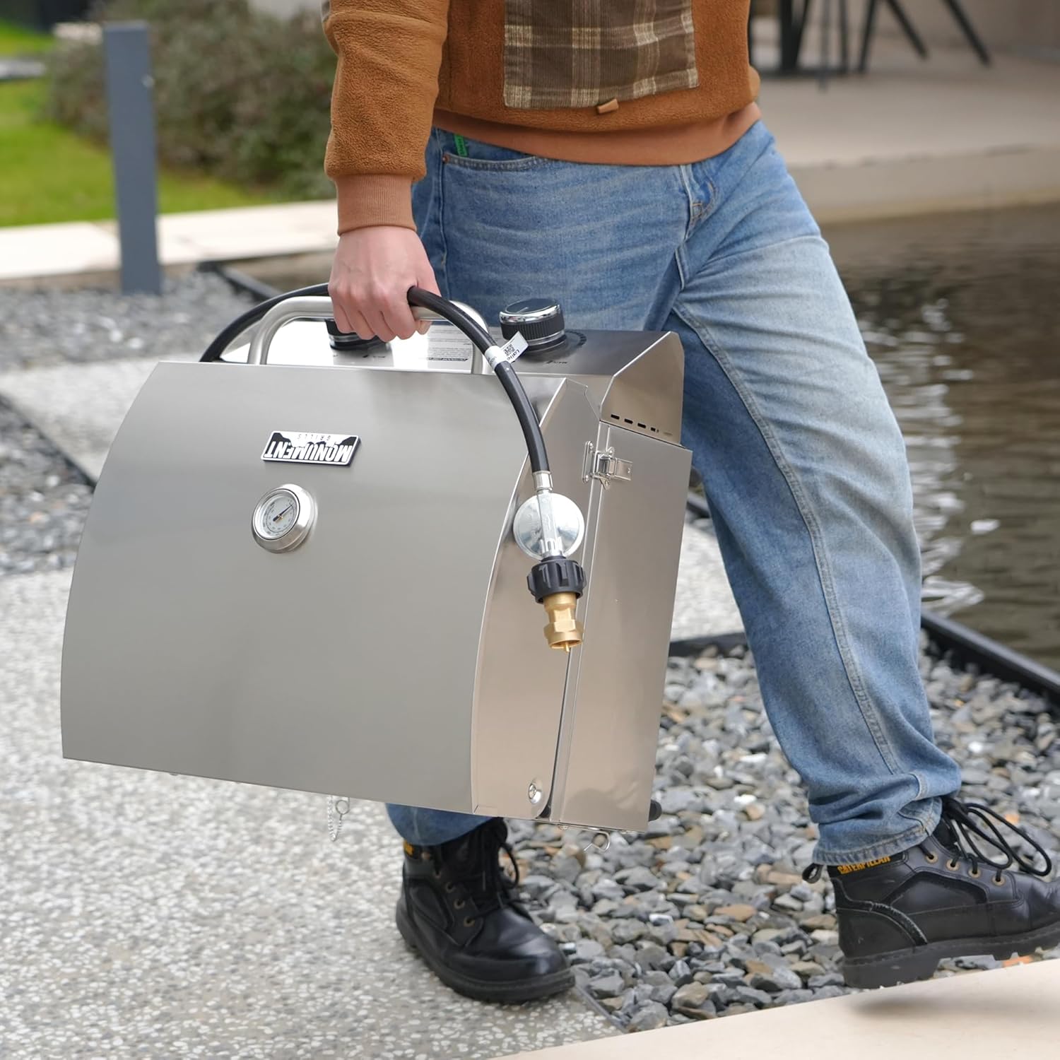 Person holding a portable propane tank on a gravel path