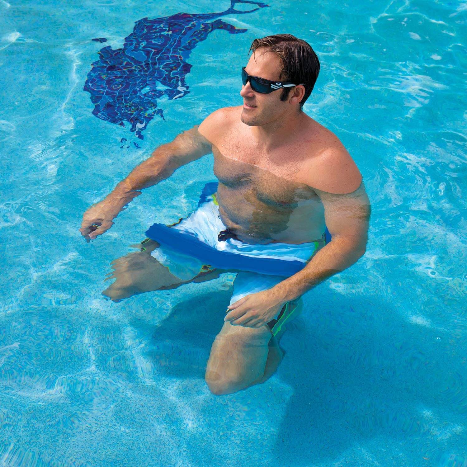 Man in a pool with a blue swim float and sunglasses
