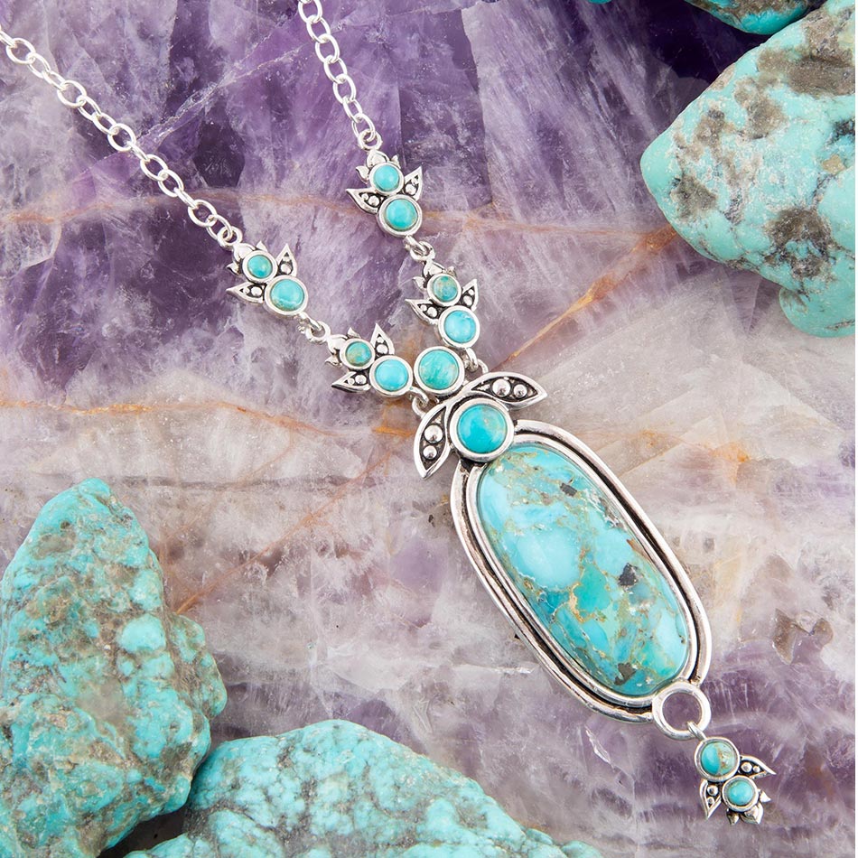 Turquoise necklace with silver chain on a textured stone background