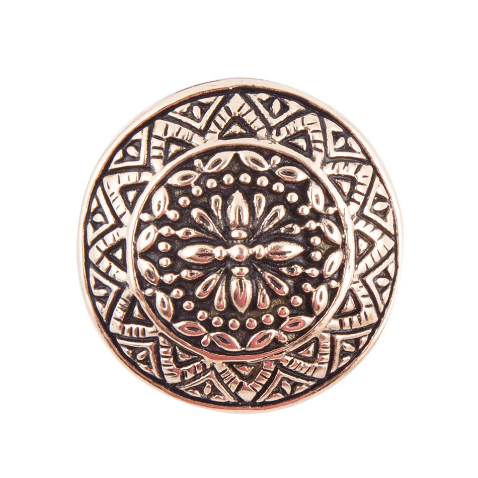 Decorative metal button with intricate circular pattern on a white background