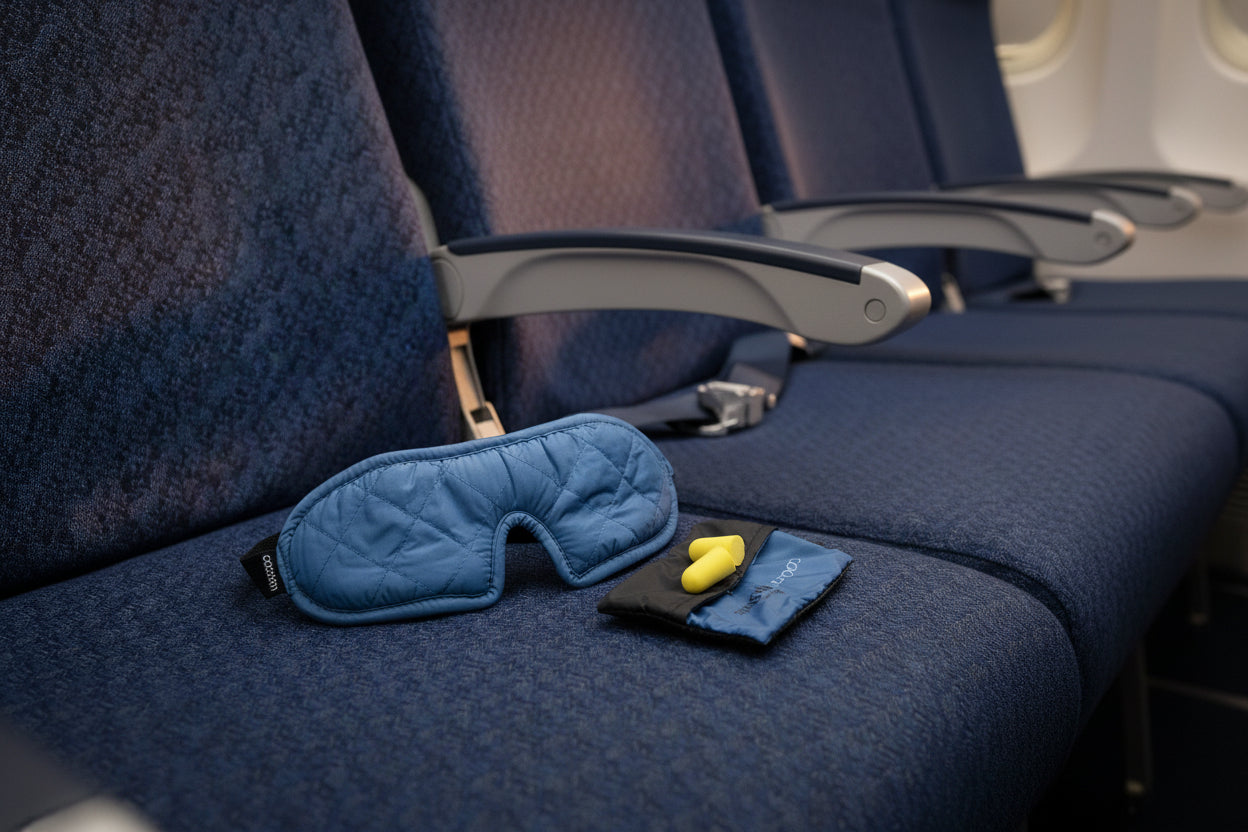 Blue quilted eye mask and earplugs in a case on a light gray background