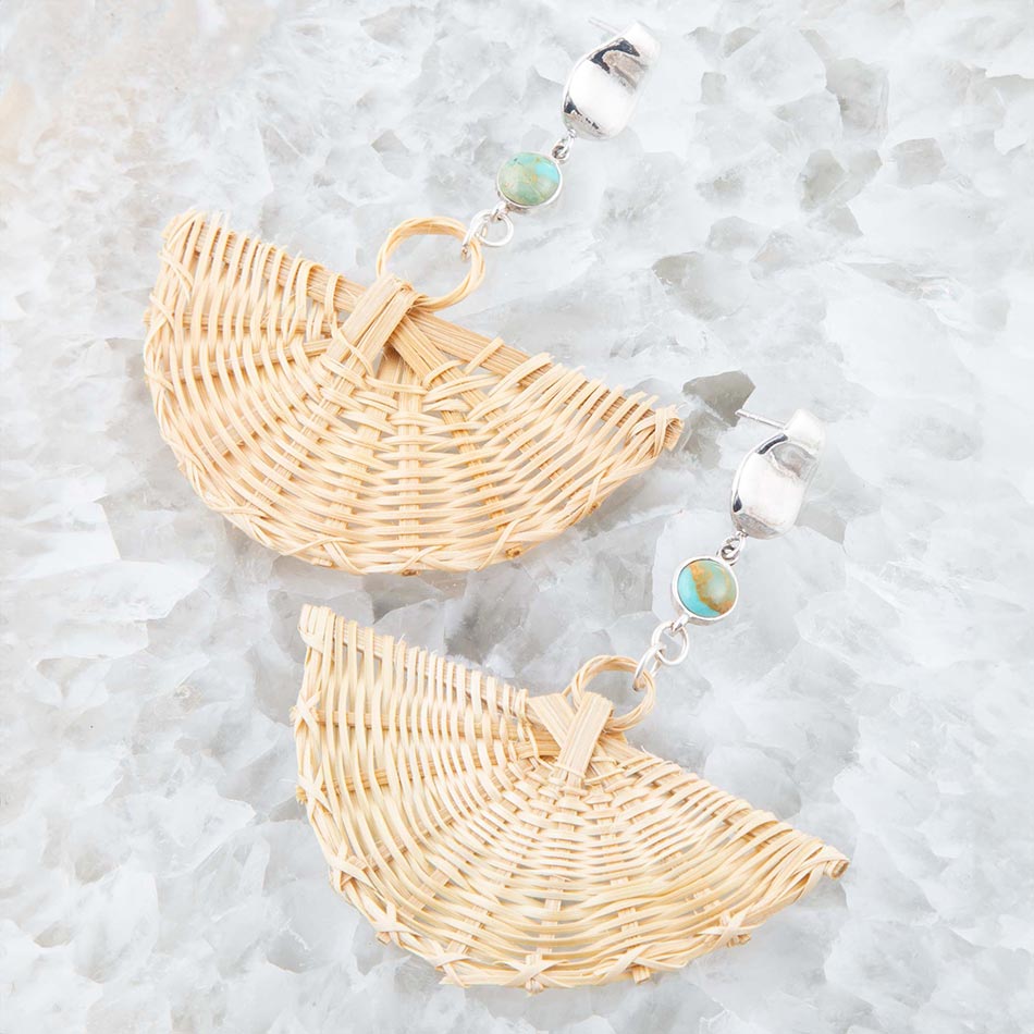 Pair of wicker earrings with stone-like beads on a textured white surface