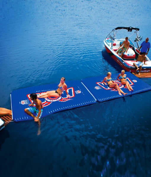 People on inflatable water mats being pulled by a boat on a lake