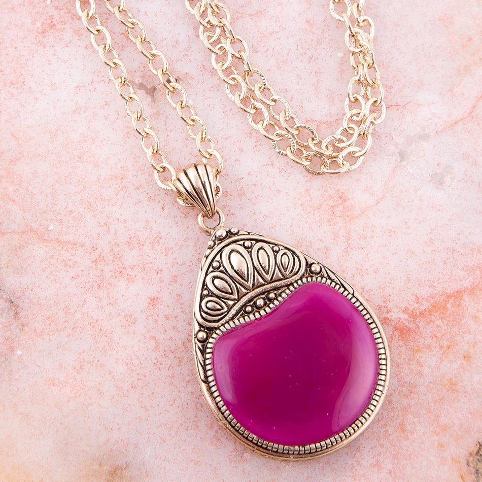 Necklace with a pink pendant on a pink marble background