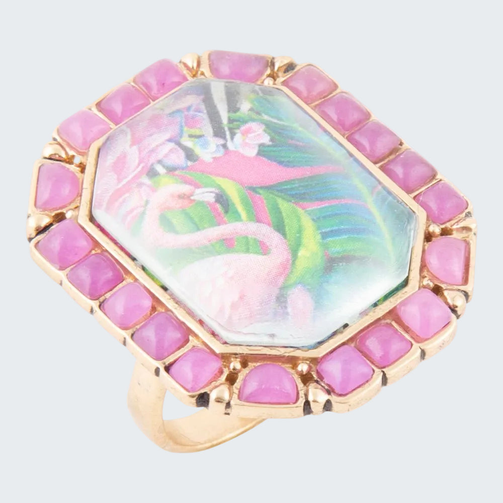 Ring with pink gemstones and a colorful flamingo design on a white background