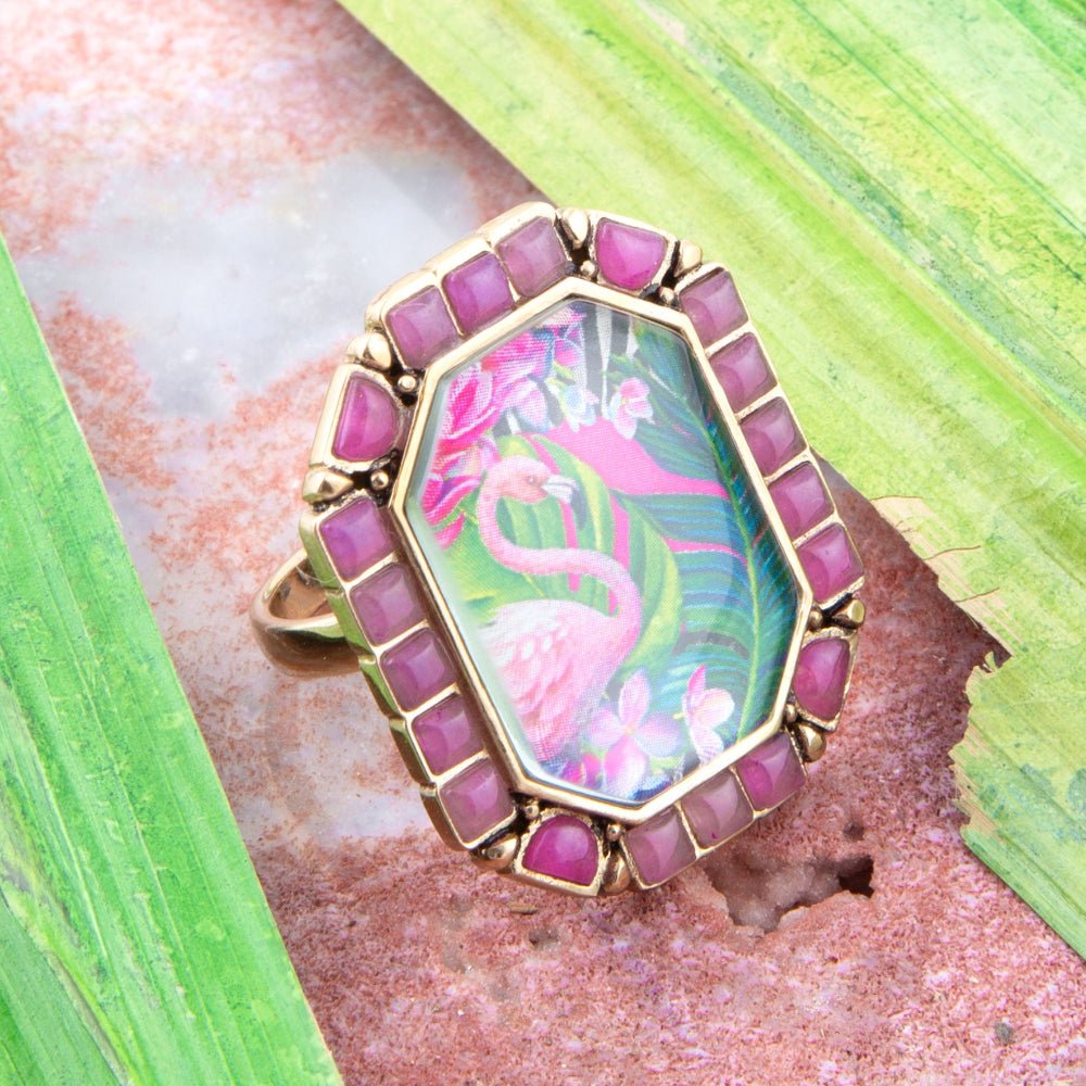 Ring with pink flamingo design and purple gemstones on a natural background