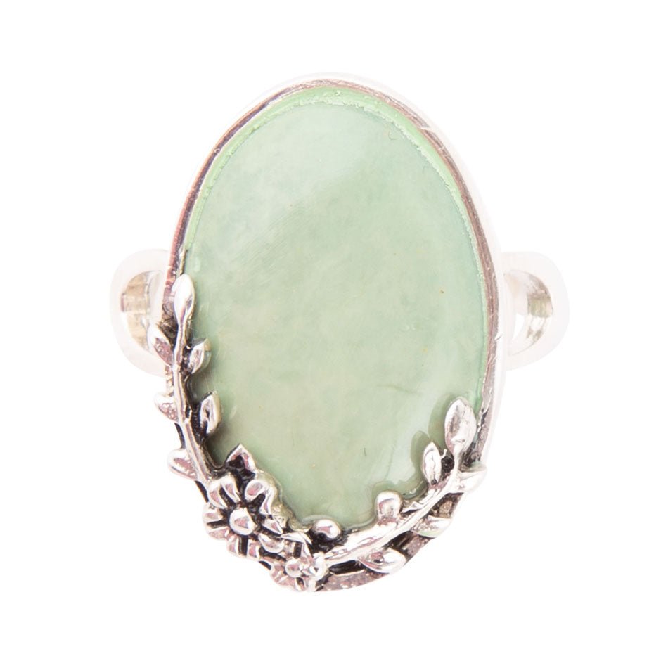 Ring with a green stone and silver floral design on a white background