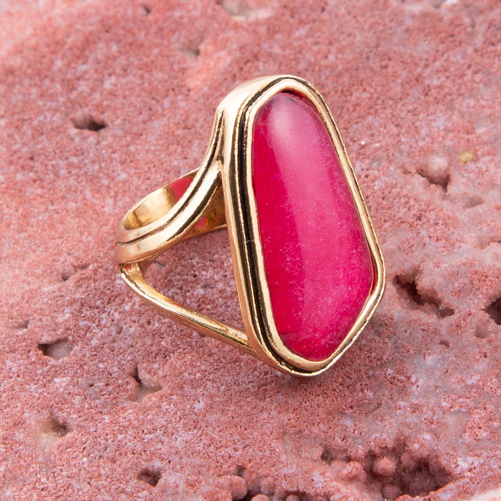 Gold ring with a pink stone on a textured pink surface