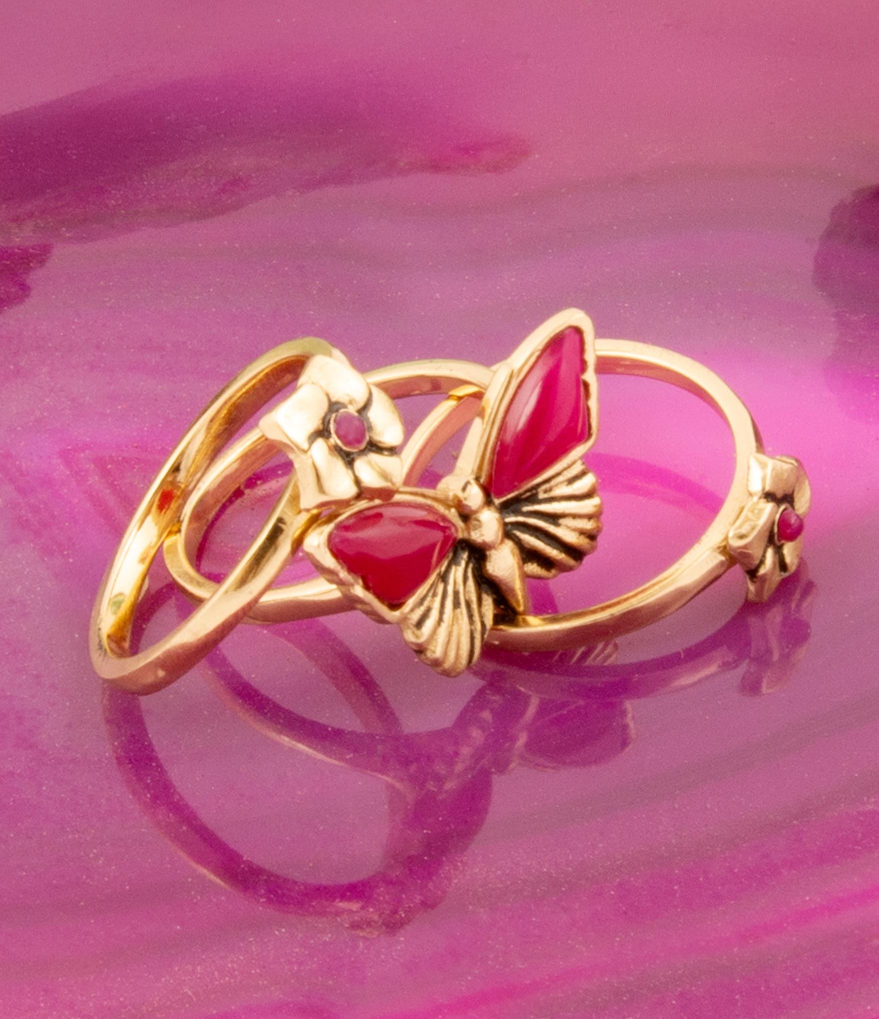Gold ring with red gemstone on a pink background