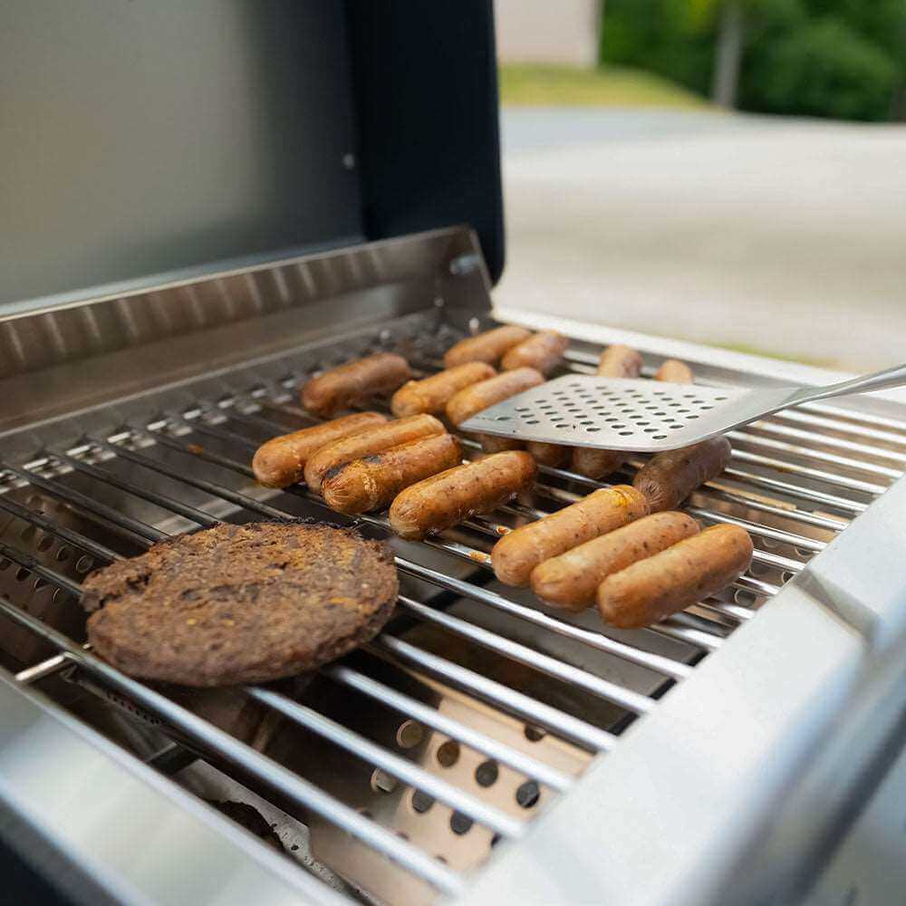 Grill with sausages and a spatula on a outdoor setting
