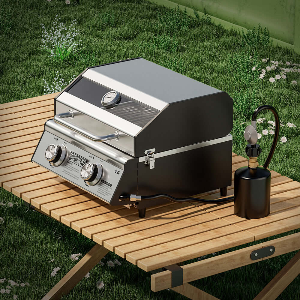Portable grill on a wooden table outdoors with grass and flowers in the background